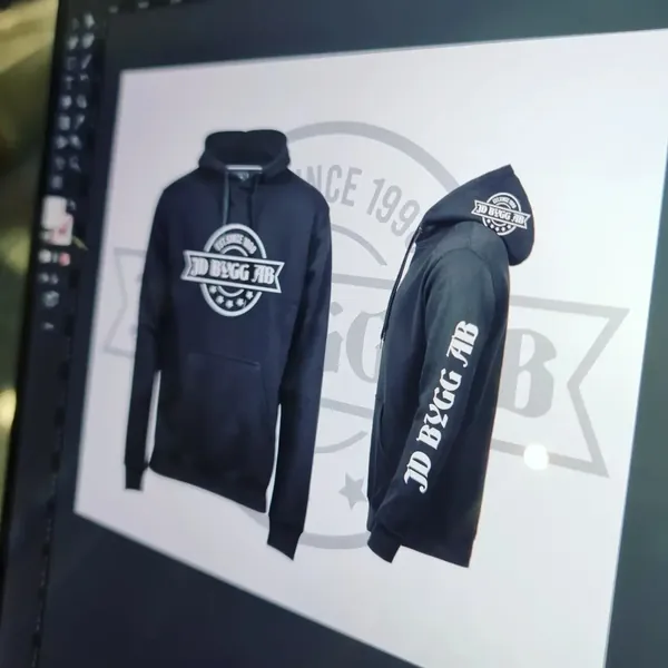 Skiss på svart hoodie med bröst-, huv- och ärmtryck för JD Bygg AB