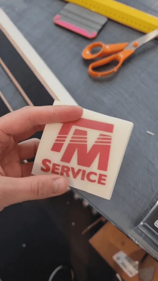 Rött enfärgat transfertryck med TM Service-logga på bärarfilm